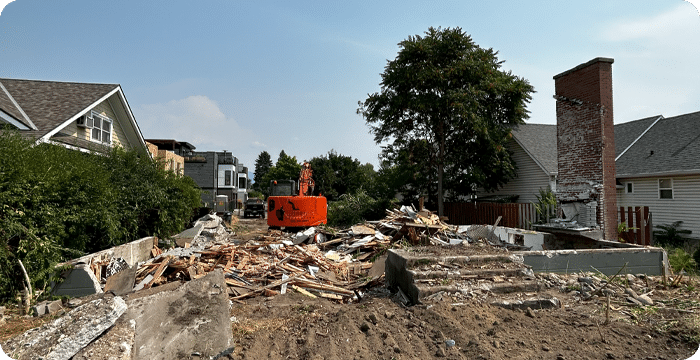 A bulldozer demolishes a house in the street, showcasing demolition services in action