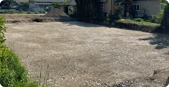 A backyard featuring a dirt driveway and a dirt yard, designed for bulk commercial landscaping purposes