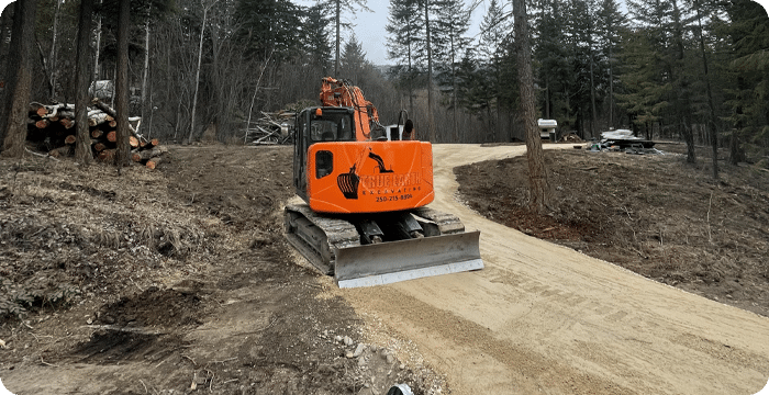A construction vehicle navigates a dirt road, actively engaged in land clearing operations