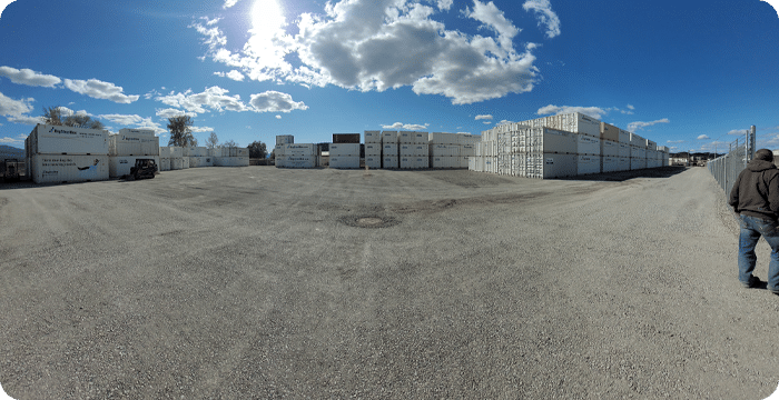 A man stands in front of a large warehouse, showcasing the Surface Prep area with equipment and materials visible